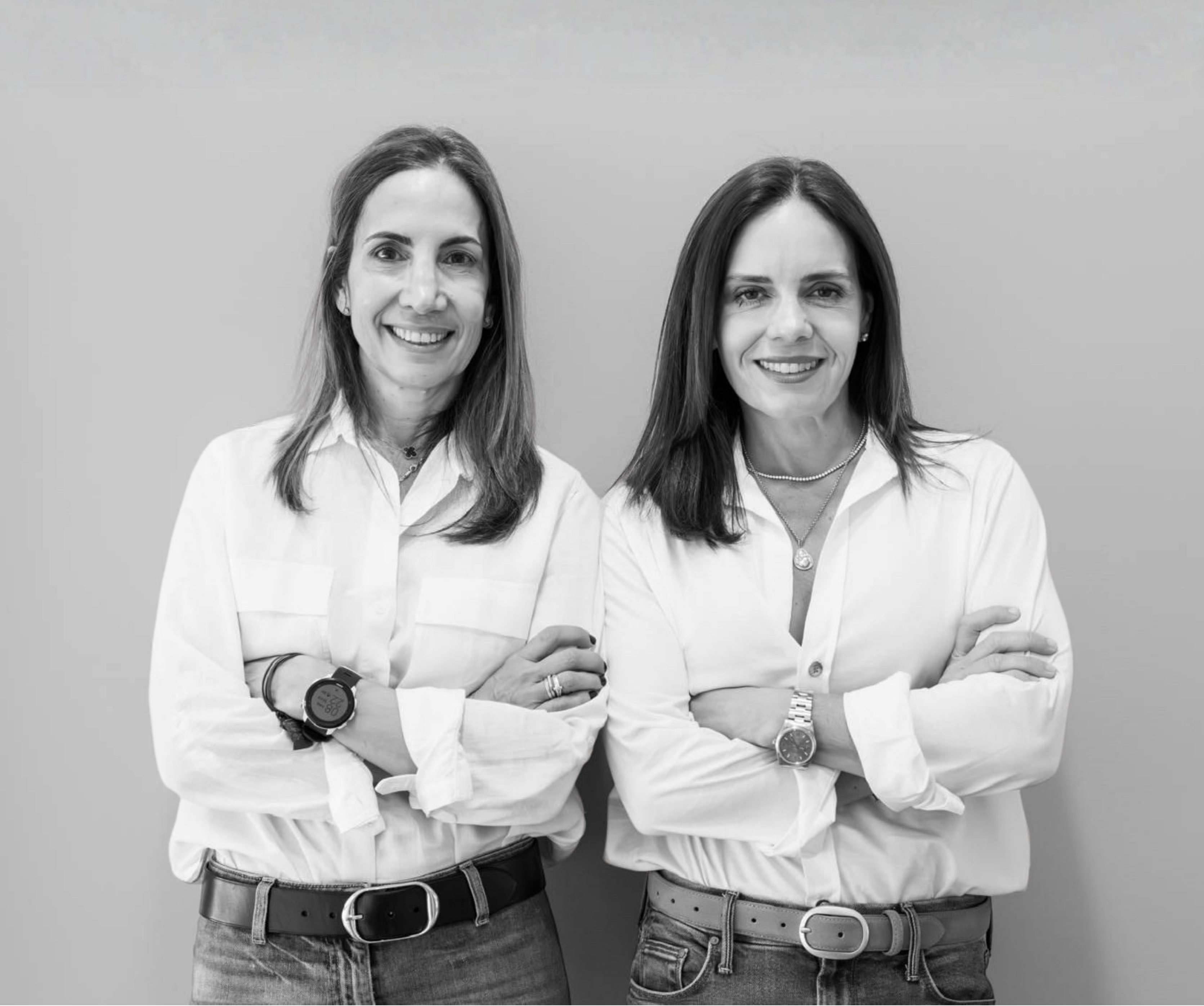 Two women from Cloud & Butter in white shirts standing against a gray background